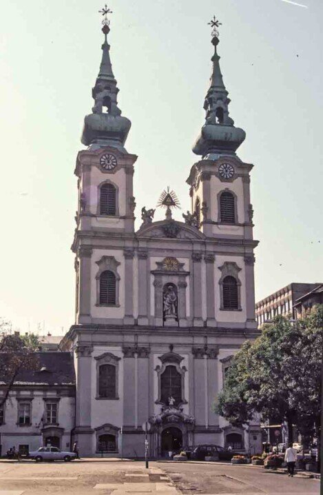 Grande edificio bianco della Chiesa di Sant'Anna a Budapest, con due eleganti torri gemelle esempio di stile barocco e dettagli raffinati.