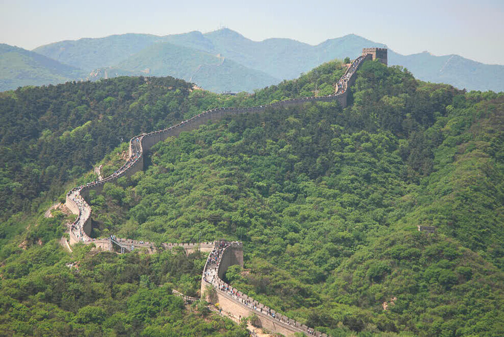 Una muraglia lunghissima che sale sulla montagna circondata da un paesaggio selvaggio e spettacolare.