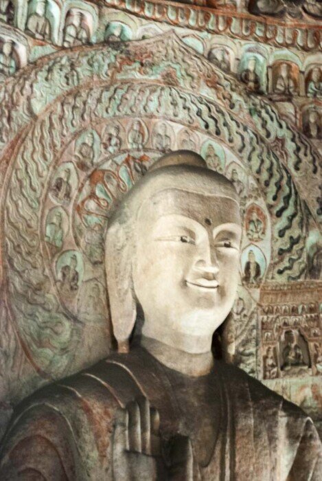 Viso di un buddha scolpito in una crotta con orecchie lunghe fino alle spalle.