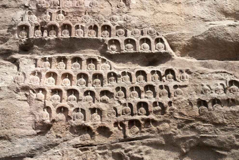 Decine di piccole statue di buddha alte pochi centimetri incise nella roccia delle grotte di Yungang