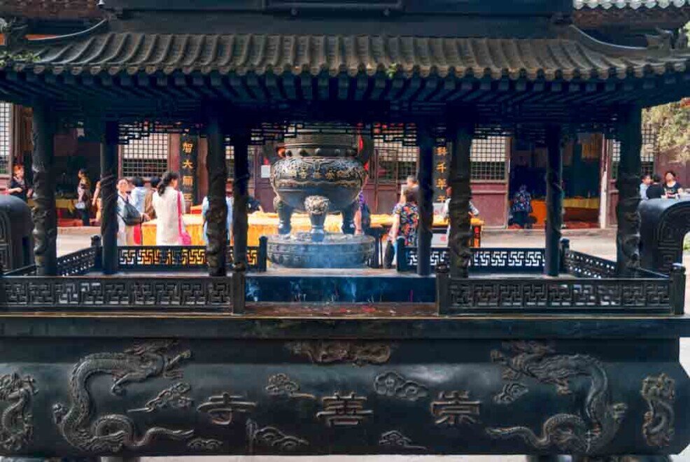 Persone attorno ad un grande incensiere acceso del tempio buddista di Chongshan