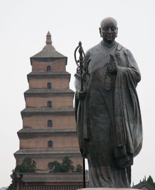 Un buddha in piedi in primo piano e sullo sfondo la Pagoda della Grande Oca Selvatica a Xi'an.
