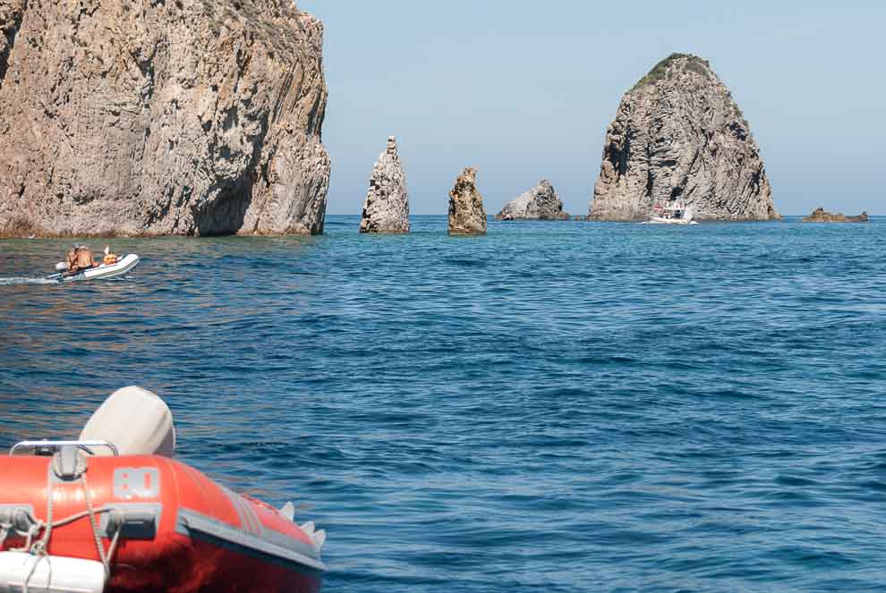 Di fronte alla poppa di una barca appaiono i faraglioni di mezzogiorno all'isola di Palmarola.