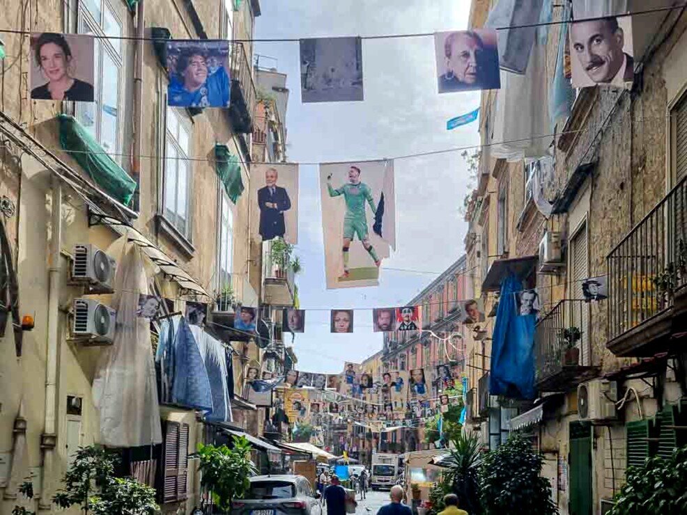 Una via di Napoli con striscioni di foto di personaggi famosi napoletani nel quartiere sanità.