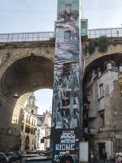 Un ponte con un ascensore per arrivarci sopra ma le pareti dell'ascensore hanno dipinto un murale dove due ragazzi si abbracciano in senso di amicizia e di pace nel rione sanità di Napoli