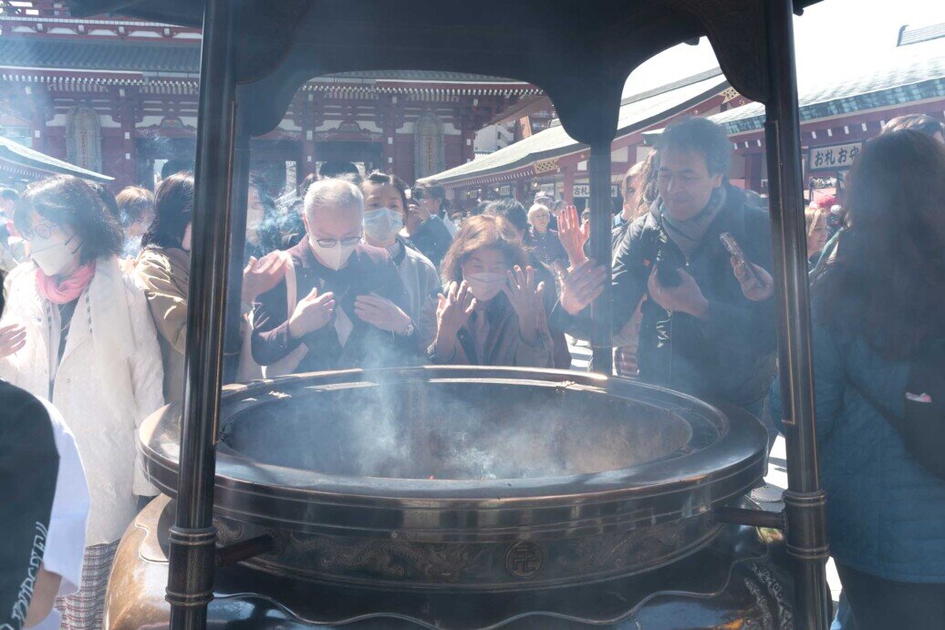 Fedeli davanti all'incensiere per attirare il fumo su di sè come auspicio di buona salute nel tempio buddista di Sensō-ji. 