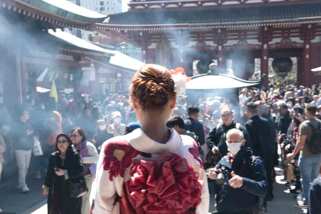 Ragazza in Kimono che guarda la piazza affollata del tempio buddista di Sensō-ji. 