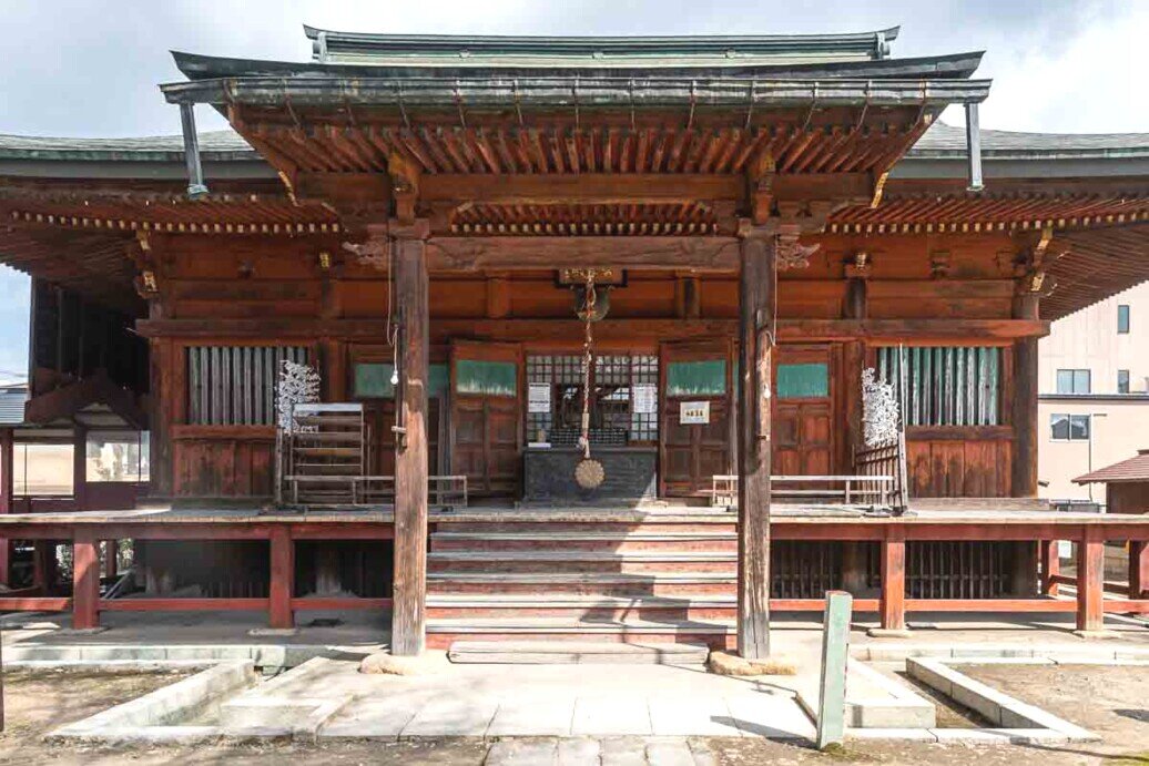 Un edificio di legno con un grande tetto e delle scale. Tempio Hida Kokubunji