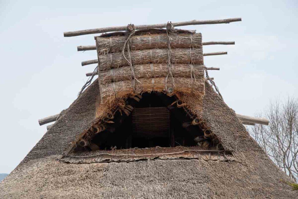 Hida Folk Village-Sottotetto di una casa agricola vista dall'esterno che ha un'ampia apertura chiudibile con quattro legni legati uno sull'altro che si abbassano o si alzano in verticale come una persiana.