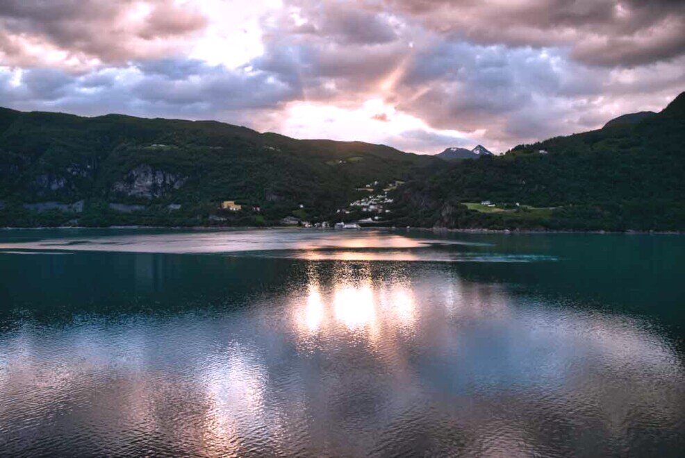 Un cielo con nuvole multicolori che si riflettono sull'acqua del GeiranderfjiordGeiranger Fjord Norvegia