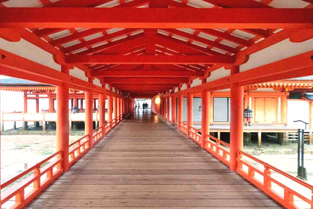 Un lungo corridoio in legno rosso che collega vari edifici del santuario di Miyajima