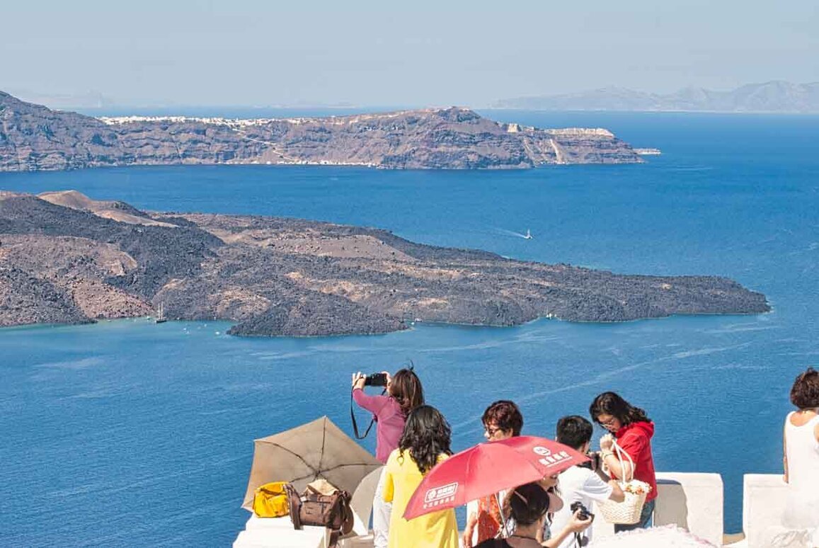 Santorini-gruppo di persone scatta foto-al panorama sulle-scogliere-della-caldera.
